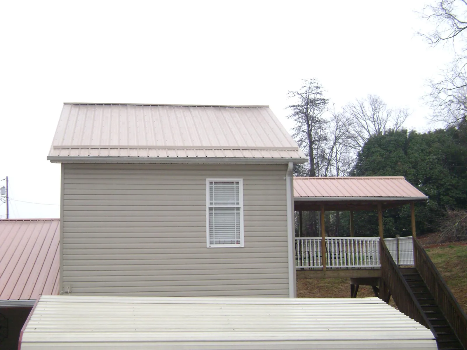 Tan metal roofs on a two story addition and attached porch, from a Roof Replacement job in Berlin